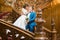 Beautiful bride tenderly touching grooms face on the stairs at rich wooden interior