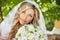 Beautiful bride with wedding bouquet of flowers outdoors in gree