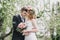 Beautiful bride in a wedding dress with bouquet and roses wreath posing with groom wearing wedding suit