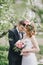 Beautiful bride in a wedding dress with bouquet and roses wreath posing with groom wearing wedding suit
