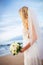 Beautiful bride in wedding dress with flowers at sunset on beaut