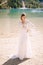 Beautiful bride in a white chiffon dress with sleeves and lace on the shore of Lake Lago di Braies in Italy. Destination