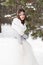 Beautiful bride in a white dress with a bouquet in a snow-covered winter forest. Portrait of the bride in nature