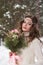 Beautiful bride in a white dress with a bouquet in a snow-covered winter forest. Portrait of the bride in nature