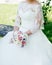 Beautiful bride in white lace wedding dress with wedding bouquet.