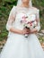 Beautiful bride in white lace wedding dress with wedding bouquet.