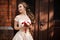 Beautiful bride in white wedding dress with a wedding bouquet standing near the wooden door