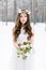 Beautiful bride. Winter wedding. Young woman in wedding dress with a floral cotton head wreath and bouquet standing in