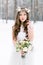 Beautiful bride. Winter wedding. Young woman in wedding dress with a floral cotton head wreath and bouquet standing in
