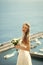Beautiful bride, woman in white dress with wedding bouquet stands on mountain top on idyllic, sunny, summer day.