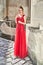 Beautiful bridesmaid brunette girl lady wearing elegant full length red chiffon bridesmaid dress with lace and holding