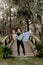 Beautiful Bridesmaid Woman in Blue Dress and Bouquet with Her Date at a Formal Wedding Party Celebration Event Outside in the Wood