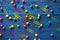 Beautiful bright background of scattered colored round pins and paper clips on a blue wooden table