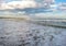 Beautiful bright blue seascape: sky, clouds, water, waves, sand, wind.