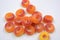 Beautiful and bright colored sweets in the form of orange and red doughnuts in sugar powder, arranged on a white matte background.