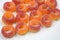 Beautiful and bright colored sweets in the form of orange and red doughnuts in sugar powder, arranged on a white matte background.