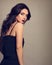 Beautiful bright makeup woman with long black curly hair style in black overalls dress, burgundy lipstick with vamp look on grey