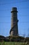 Beautiful bright vertical view of Ballycorus lead mining and smelting chimney tower seen through wire fence, Ballycorus