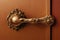 Beautiful bronze door handle with twisted decorations on brown door