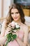 Beautiful brown-haired young girl with a bouquet of roses, professional makeup and styling. Romantic and gentle image.