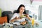 A beautiful brunette 30-aged Asian woman, sitting at the table at Japanese cafe and holding plate with tasty delicious