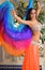 Beautiful brunette, belly dancer with rainbow shawl in the arabic harem interior