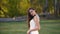 Beautiful brunette bride with deep look is looking right and begins to smiling in sunny rays at the autumn park.