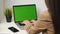 Beautiful brunette caucasian appearance working in the office on a laptop on a green background. Back shot