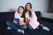 Beautiful brunette caucasian mother and daughter sit together in room. They watch movie. People hold popcorn baskets and