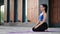 Beautiful brunette fitness woman sitting on mat floor relaxing yoga meditation outdoor building