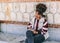 Beautiful brunette girl with afro hair writes in her diary relaxingly while sitting next to a large stone and brick wall