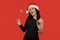 Beautiful brunette girl in a black dress and Santa hat holding glass of champagne and bengal lights.