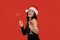Beautiful brunette girl in a black dress and Santa hat holding glass of champagne and bengal lights.