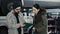 A beautiful brunette girl, a client of a car service center, takes a car from a repair and signs documents with a car