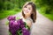 Beautiful brunette girl with a lilac flowers relaxing and enjoying life in nature. Outdoor shot. Copyspace