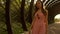 Beautiful brunette girl in pink dress walks though arched passage. Slow motion steadicam clip