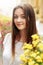 Beautiful brunette girl posing and smiling in soft sunny light at flowers in city street, joyful moments