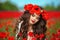 Beautiful brunette girl in red poppy flowers field nature background. Beauty outdoor portrait. Attractive young woman with red li