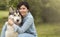 Beautiful brunette girl sitting on the grass with her funny friend malamute dog