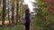 Beautiful brunette girl walking through autumn woods holding a picnic basket. Sunny day. 4K steadicam video