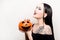 A beautiful brunette holds a pumpkin in her hands and smiles. Halloween costume party. Cobwebs for eyelashes, witch. Woman on