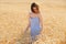 Beautiful brunette lady in blue dress walking in wheat field at sunset. Autumn portrait