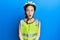 Beautiful brunette little girl wearing bike helmet and reflective vest afraid and shocked with surprise expression, fear and