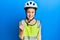 Beautiful brunette little girl wearing bike helmet and reflective vest angry and mad raising fist frustrated and furious while