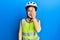 Beautiful brunette little girl wearing bike helmet and reflective vest covering one eye with hand, confident smile on face and