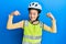 Beautiful brunette little girl wearing bike helmet and reflective vest showing arms muscles smiling proud