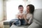 Beautiful brunette mom and son hugging sofa