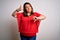 Beautiful brunette plus size woman wearing casual red t-shirt over isolated white background Doing thumbs up and down,