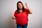 Beautiful brunette plus size woman wearing casual red t-shirt over isolated white background Shouting frustrated with rage, hands