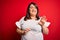 Beautiful brunette plus size woman wearing casual t-shirt over isolated red background disgusted expression, displeased and